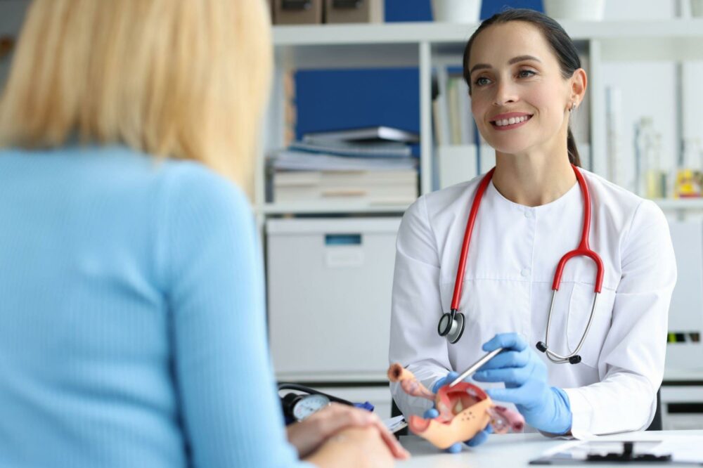 Gynecologist holds model of female reproductive system of uterus and consults patient. Gynecological diseases in women concept